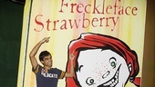 Sanjaya Malakar shows off the giant Freckleface Strawberry book cover that graces the stage at the off-Broadway production. 