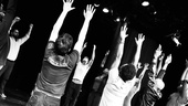 The company of Hit the Wall raises their hands in protest! (Actually, they are just continuing to stretch before movement rehearsal.)